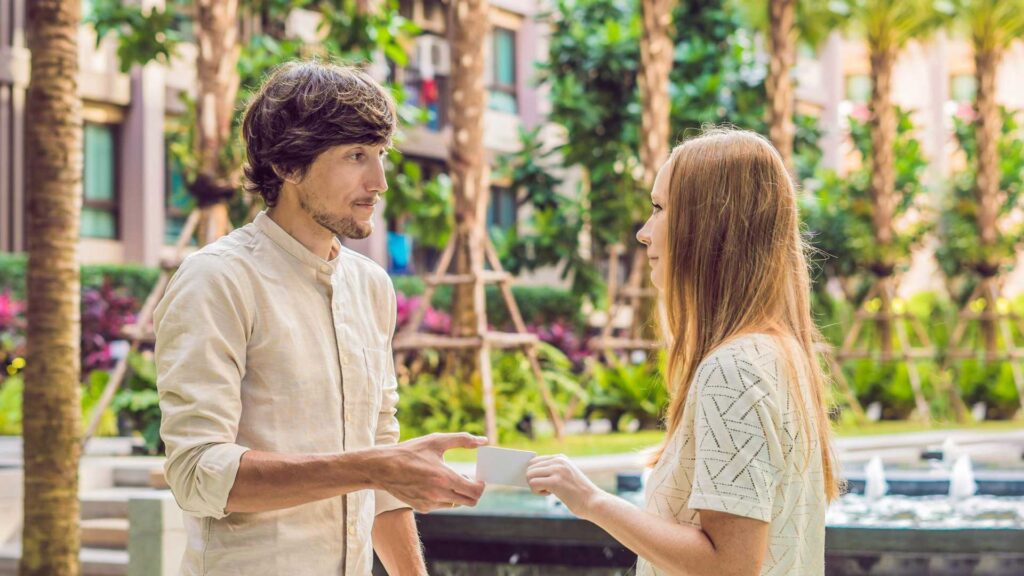 A woman gives to a man security key card or business card