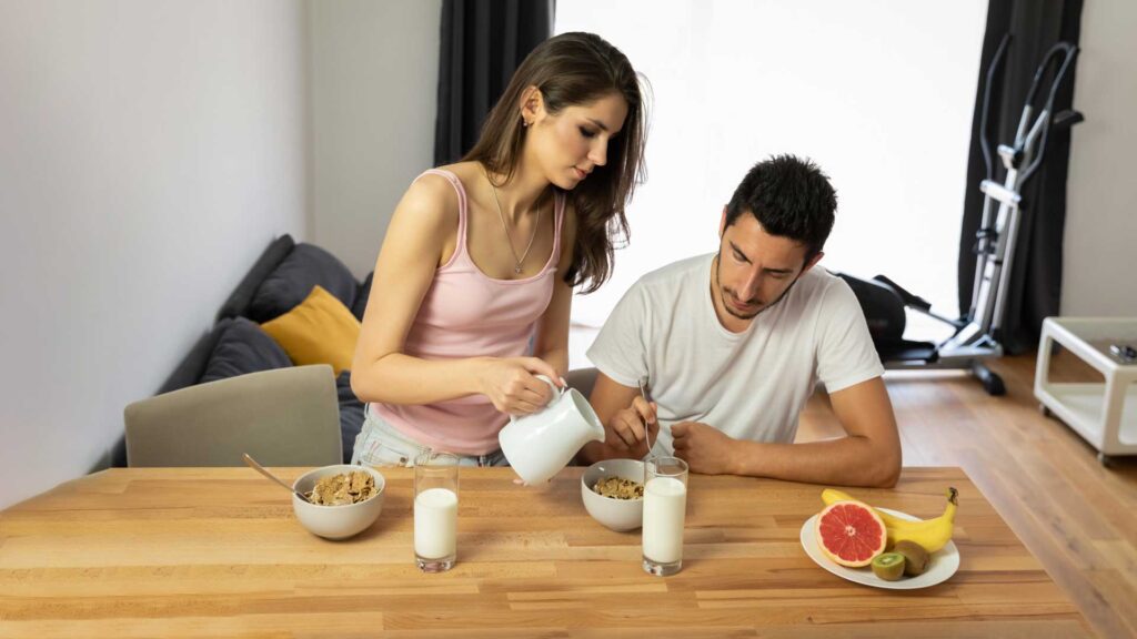 Young Beautiful Couple Eats Breakfast Cereal with Berries and Milk.