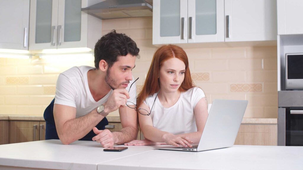 Learn and Grow Young Couple working with laptop at home in kitchen